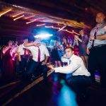 Crowded dance floor with DJ performing under dramatic stage lighting