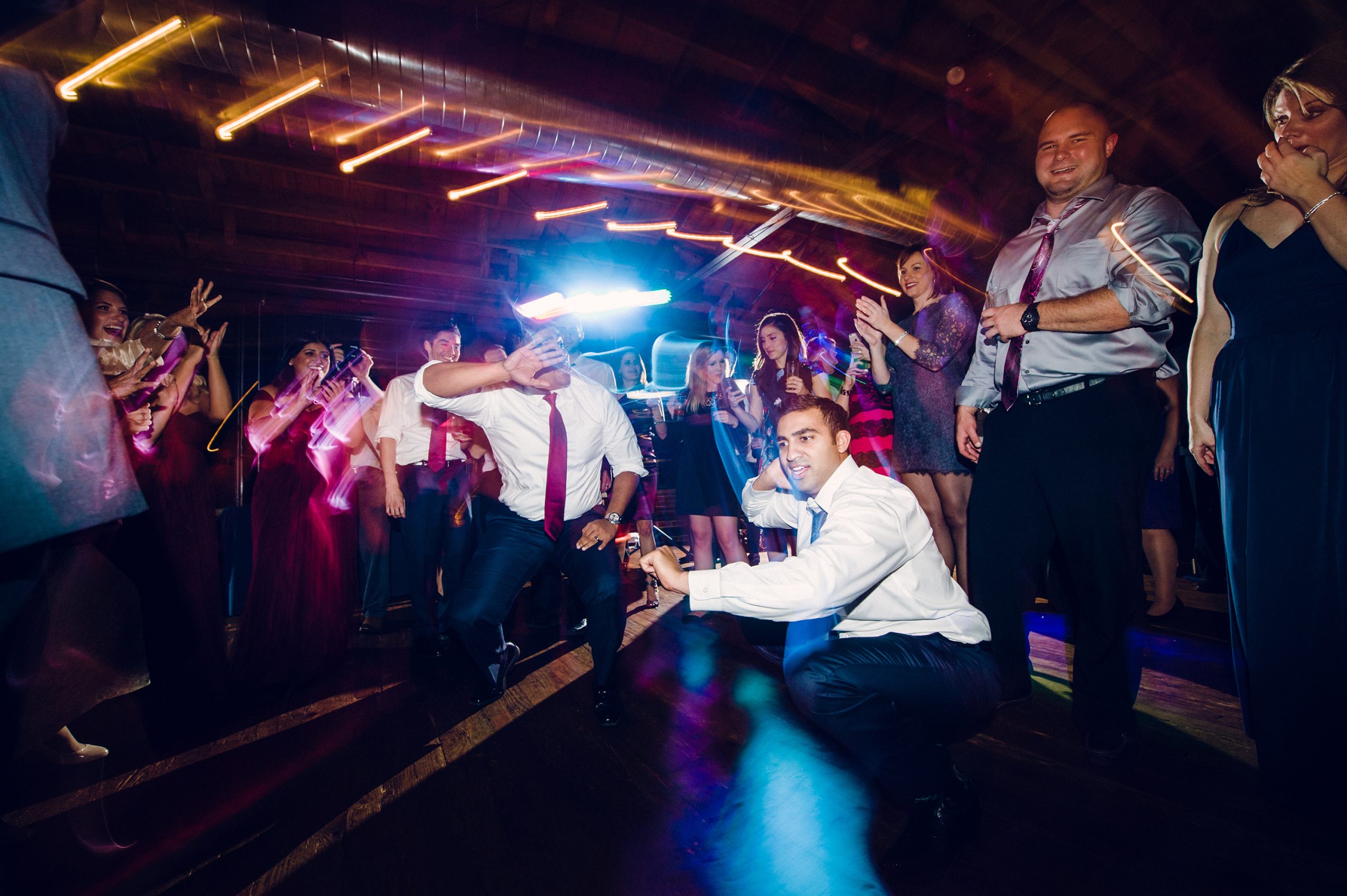 Crowded dance floor with DJ performing under dramatic stage lighting