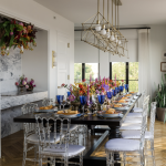 Elegant reception table with clear ghost chairs, tall candles, and colorful floral centerpieces