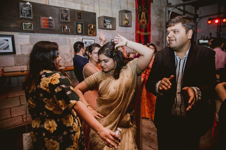 Wedding guests dancing together at reception venue with industrial brick walls and Atlanta United decor