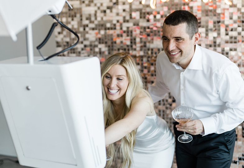 Bride and groom using interactive photo booth at wedding reception