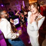 Bride dancing with wedding guests on purple-lit dance floor