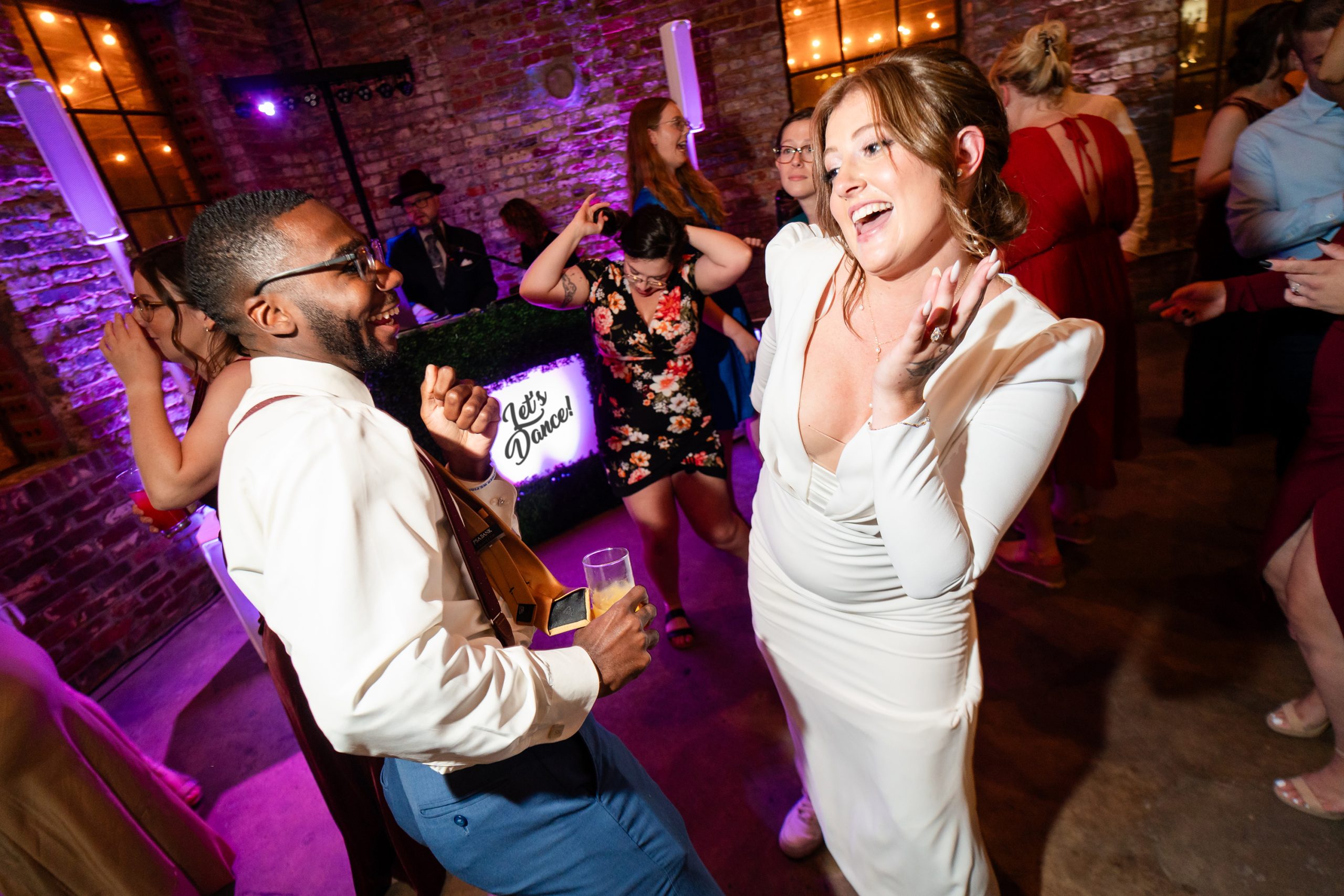 Bride dancing with wedding guests on purple-lit dance floor