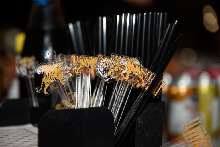 Tiger-themed acrylic drink stirrers arranged in black holder at bar setup
