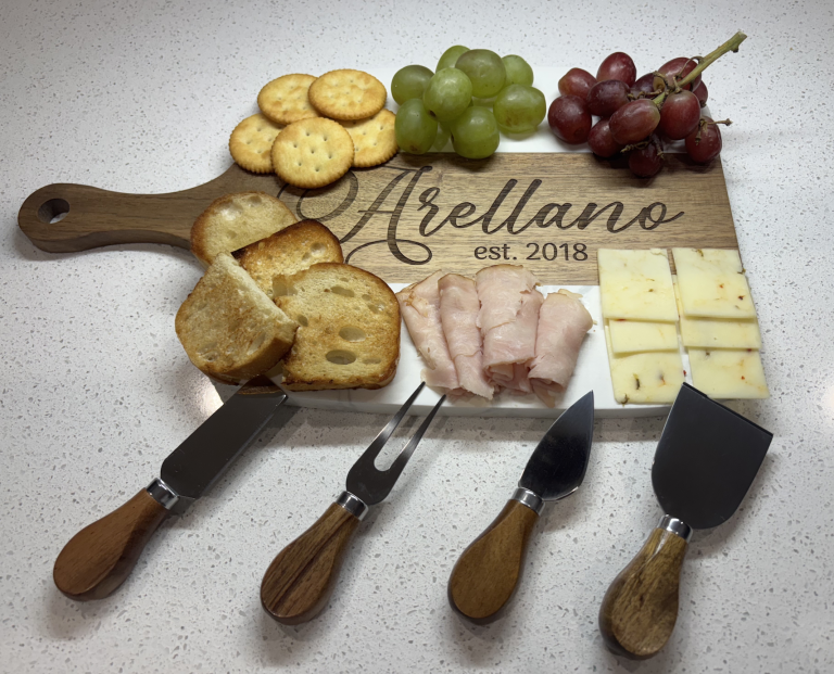 Personalized Arellano charcuterie board with grapes, crackers, cheese, and meat alongside cheese knives