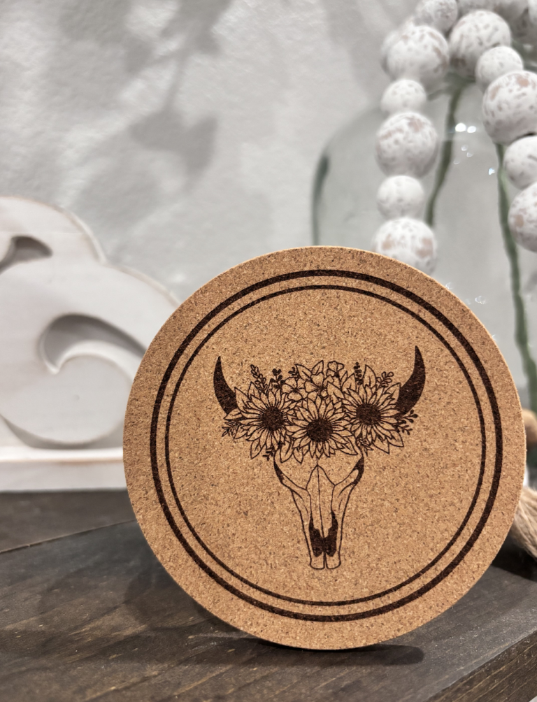 Cork coaster with engraved cow skull adorned with sunflowers and wildflowers in southwestern wedding decor style