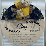 Personalized door sign with "The Clay Family" text, floral ribbon bow, and Spanish Bible verse from Isaiah 33:22