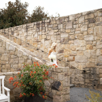 Outdoor stone staircase with metal railings, white bench, and flowering plants