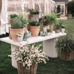 Rustic outdoor display table with terracotta pots, flowering plants, and decorative baskets