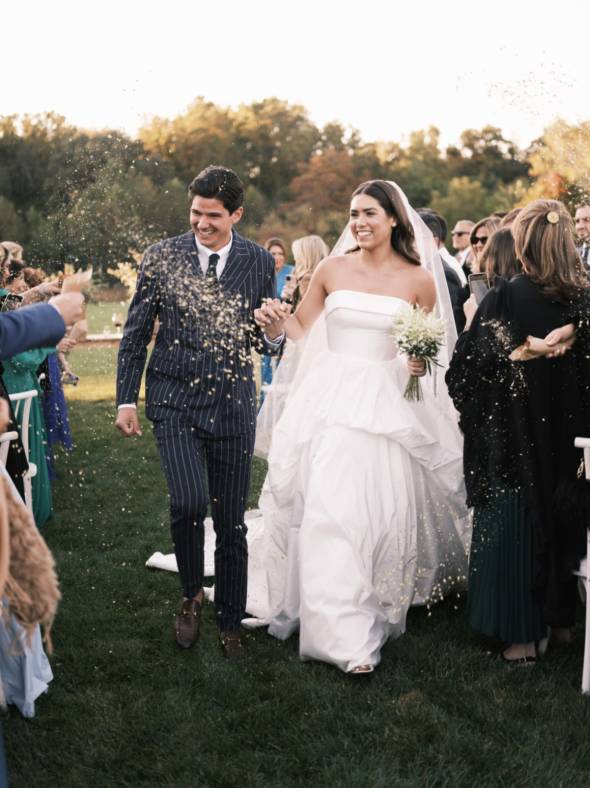 Newlyweds walking down aisle through confetti shower after outdoor ceremony at golden hour in Northern Virginia