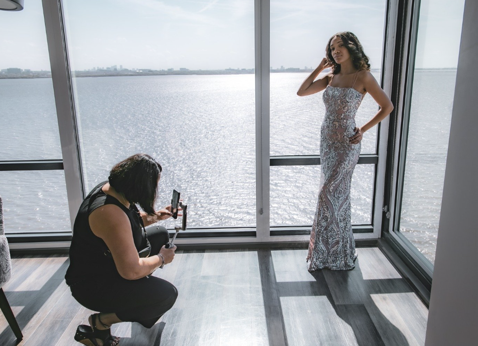 Wedding content creator filming bride in beaded gown by waterfront windows
