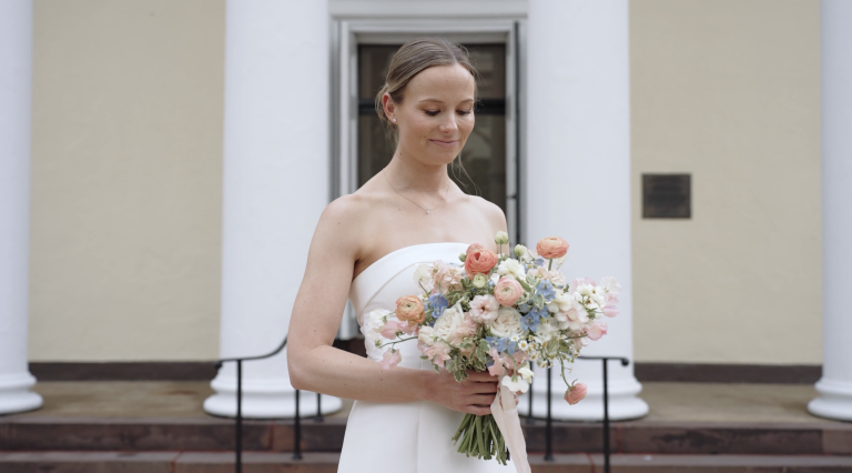 Bride in strapless white gown holding pastel bouquet of pink, blue, and white flowers