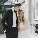 Bride and groom posing in contemporary white hallway with modern artwork, formal wedding attire