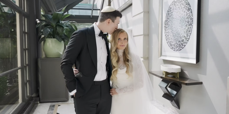 Bride and groom posing in contemporary white hallway with modern artwork, formal wedding attire