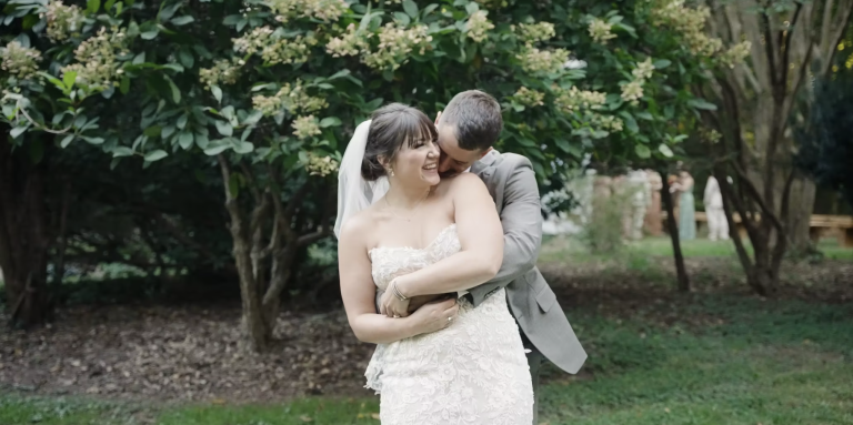Bride and groom sharing an intimate moment in lush garden, groom kissing bride's cheek while embracing