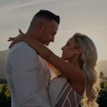 Couple embracing in vineyard at sunset with mountains in background