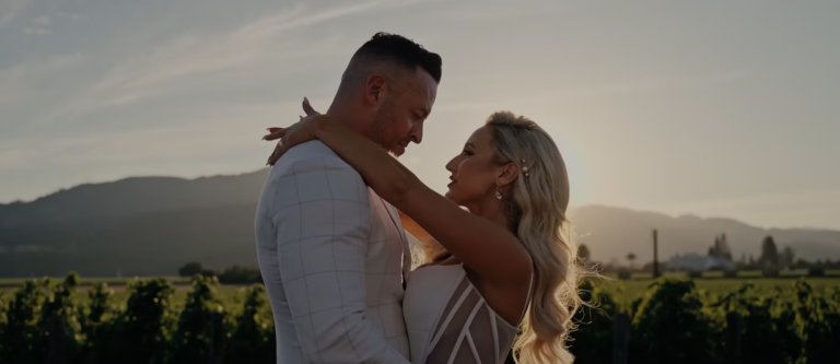 Couple embracing in vineyard at sunset with mountains in background