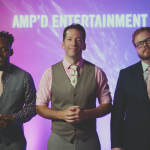 AMP'D Entertainment team members in formal attire with professional stage lighting
