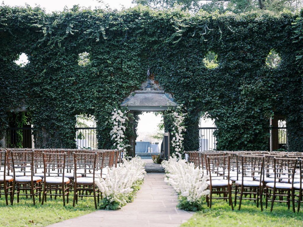 Elegant outdoor wedding ceremony setup with white floral aisle and ivy-covered wall in Northern Virginia