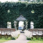 Elegant outdoor wedding ceremony setup with white floral aisle and ivy-covered wall in Northern Virginia