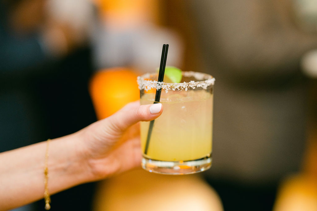 Guest holding a margarita with salt rim and lime garnish at Victoria and Anthony's wedding reception