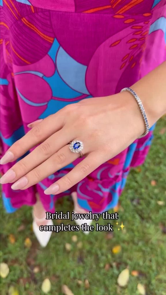 Blue sapphire engagement ring with diamond halo and matching tennis bracelet displayed against vibrant floral dress