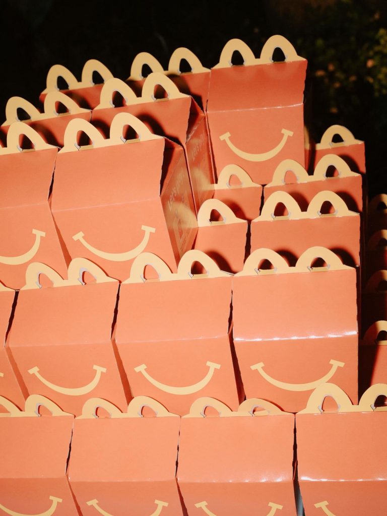 Coral pink gift bags with rainbow smile design stacked for guests