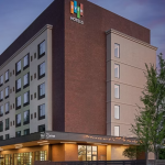 Modern EVEN Hotels exterior at dusk with illuminated entrance and contemporary brick and beige facade