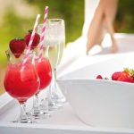 Strawberry cocktails with pink striped straws and champagne glasses at outdoor wedding reception