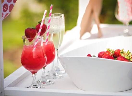 Strawberry cocktails with pink striped straws and champagne glasses at outdoor wedding reception