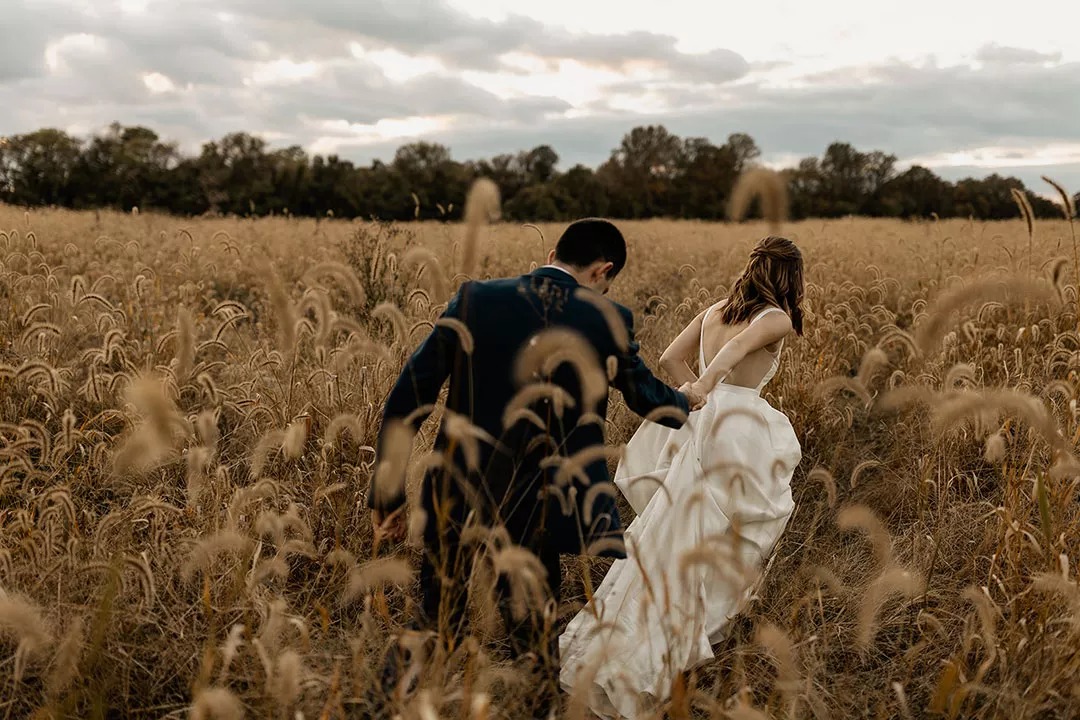 Husband and wife in grassy knoll after wedding ceremony