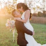 Groom lifting bride in romantic embrace during golden hour wedding portrait