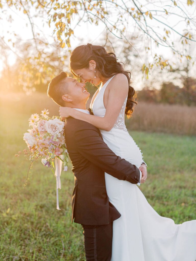 Groom lifting bride in romantic embrace during golden hour wedding portrait