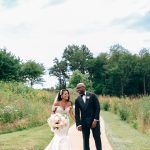 Bride and groom walking together on tree-lined path through natural field at Salamander Resort