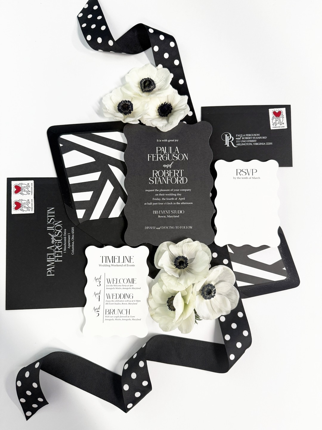 Black and white wedding invitation suite with geometric patterns, white anemone flowers, and polka dot ribbon