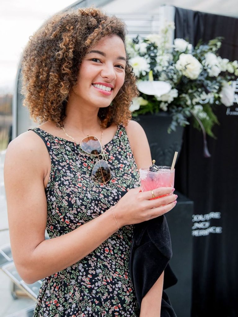 Woman celebrating at catered wedding reception with specialty cocktail and elegant floral decor