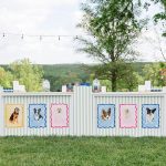 Two striped bar stations with dog portrait decorations, vibrant floral arrangements, and beverage dispensers in outdoor garden setting