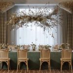 Wedding reception table with wood chairs, green velvet linens, and dramatic overhead floral canopy installation