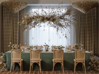 Wedding reception table with wood chairs, green velvet linens, and dramatic overhead floral canopy installation