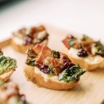 Crispy bruschetta topped with bacon, cranberries, and greens on toasted baguette slices