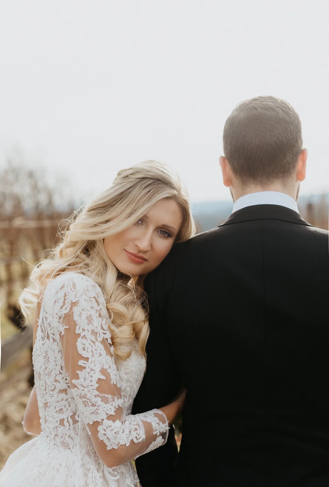Bride with soft curled blonde hair and natural makeup wearing a lace wedding dress with groom in Northern Virginia