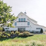 White barn-style wedding venue with cupola and black-trimmed windows surrounded by landscaped grounds in Northern Virginia