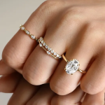 Hand wearing emerald-cut diamond solitaire engagement ring with delicate pavé wedding band