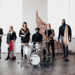 Diamond Empire Band members with instruments in industrial venue with exposed brick