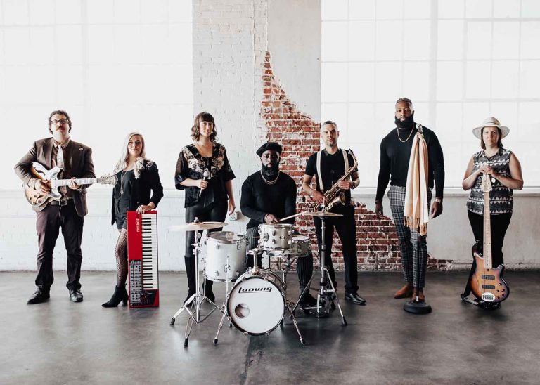Diamond Empire Band members with instruments in industrial venue with exposed brick