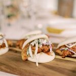 Asian-inspired shrimp bao buns garnished with pickled vegetables and microgreens on wooden board
