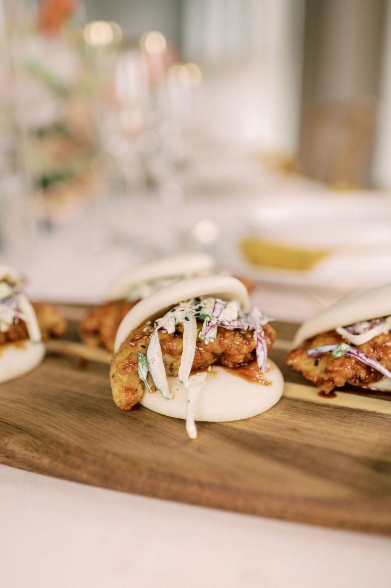 Asian-inspired shrimp bao buns garnished with pickled vegetables and microgreens on wooden board