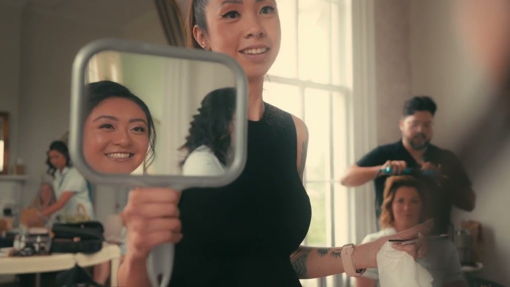 Smiling bride looking in handheld mirror during wedding day preparations