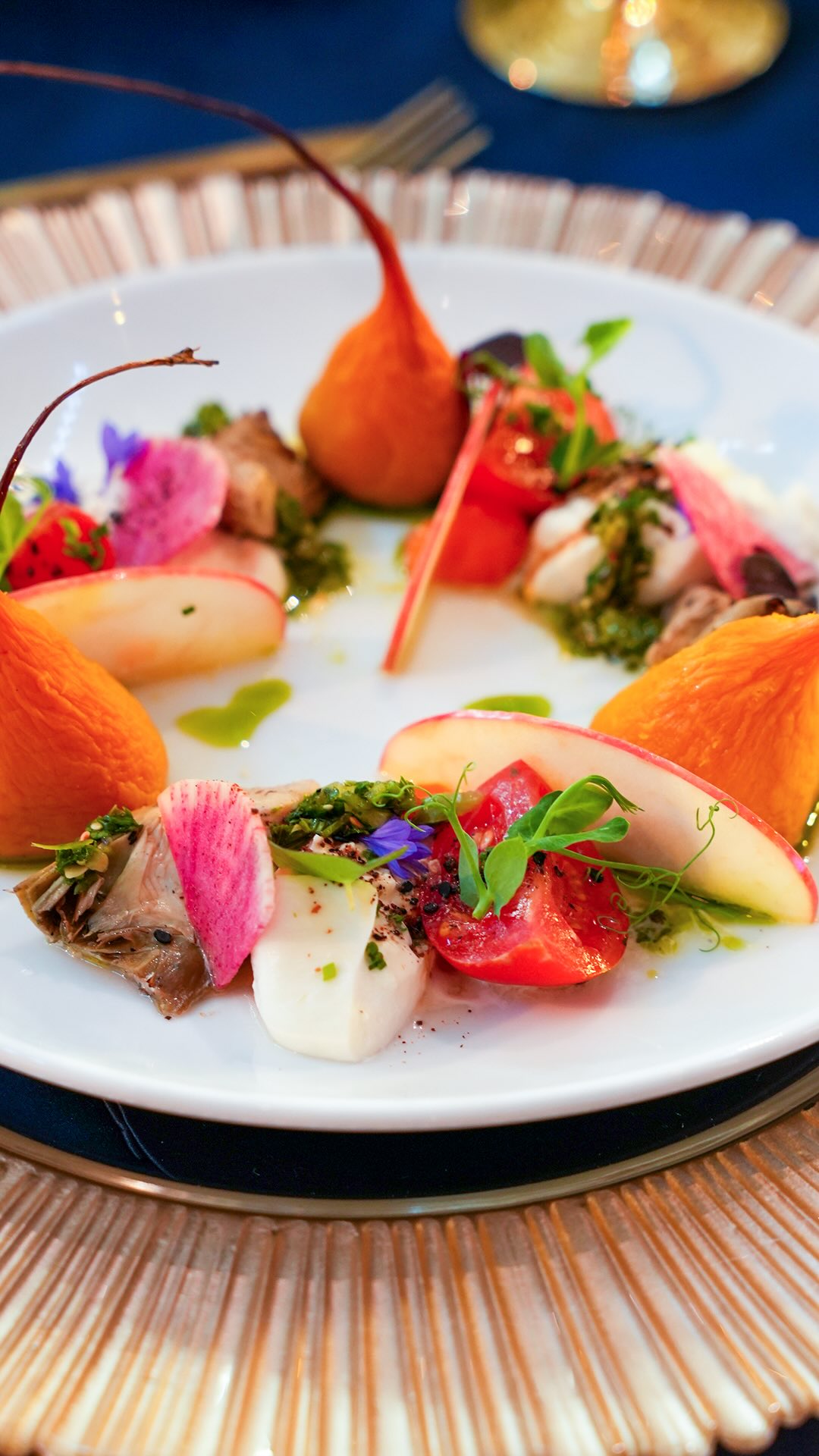 Artfully plated appetizer with seared tuna, poached pear, watermelon radish, and edible flowers
