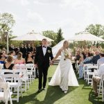 Outdoor wedding ceremony on lawn with white chairs and tent reception space